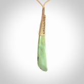 This photo shows a medium sized jade drop shaped pendant. It a a lovely varied green and light orange New Zealand Flower jade. The cord is a four plait beige and is adjustable in length.
